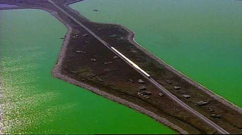 Helicopter shot of train going through crossway, with green water on either side 스톡 동영상 29804184