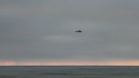 Helicopter at sunset over ocean waves Stock Footage 10729090