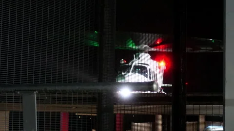 Helicopter Taking Off at Night in Rain Seen Through Fence Stock Footage 329979029