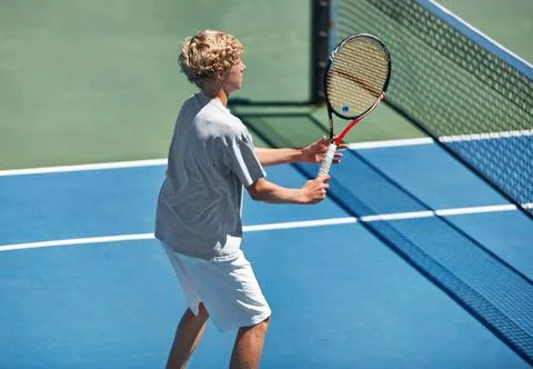 Hell be a start one day. a young boy playing tennis on a sunny day. Stock Photos