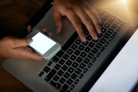 Hell crack that code. High angle shot of a hacker using a cellphone to cracki Stock Photos
