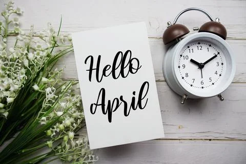 Hello April text message with flower and alarm clock on wooden background Stock Photos