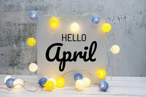 Hello April text message with LED cotton ball decoration on wooden background Stock Photos