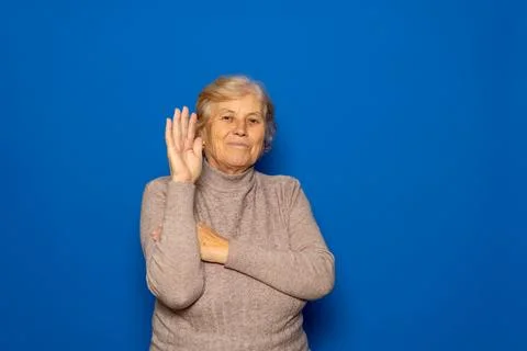 Hello concept. A happy, smiling, elderly Caucasian woman in her 70s waves w.. Stock Photos