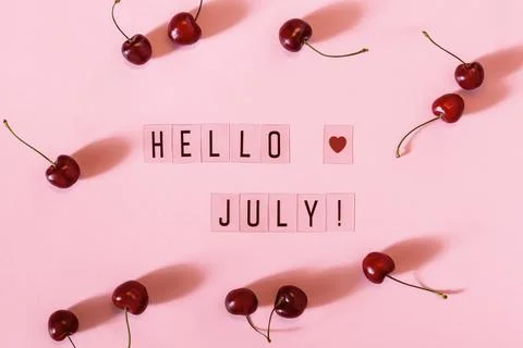 Hello July text and cherry berry scattering on pink background. Hello July Stock Photos