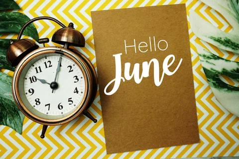 Hello June typography text on paper card with alarm clock and Monstera leave 库存照片