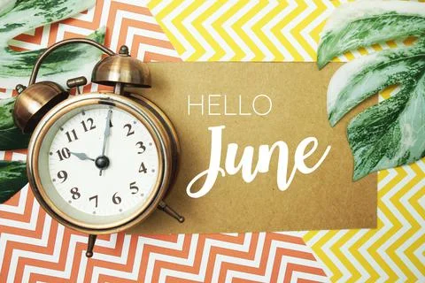 Hello June typography text on paper card with alarm clock and Monstera leave 库存照片