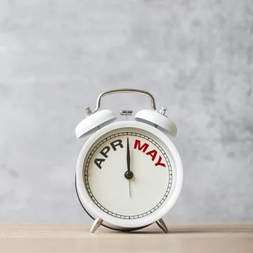 Hello May Changed from April month with vintage alarm clock on table backgr.. Stock Photos