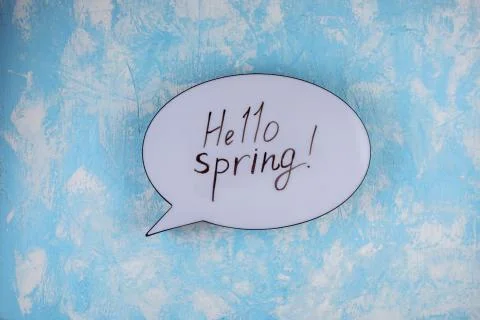 Hello spring inscription on the speech bubble. Blue textured background. Stock Photos