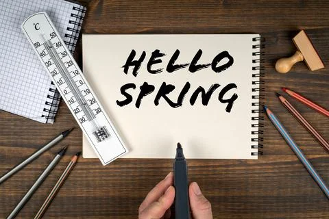Hello Spring. Thermometer and office supplies on a wooden table Stock Photos