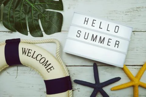 Hello Summer text in light box with green leave, starfish and lifebuoy decora Stock Photos