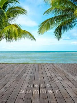 Hello Summer text on wooden deck overlooking tropical beach with palm trees.. Stock Photos