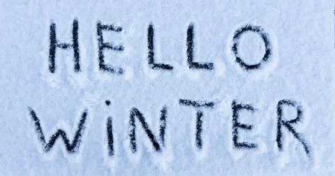 Hello Winter words written on the surface of a snow field. Stock Photos