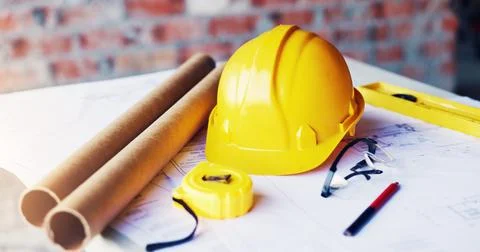 Helmet, construction and tools in empty office for engineering, blueprint d.. Stock Photos