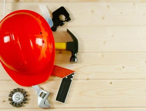 Helmet, hammer, an adjustable spanner and other tool on a wooden background. Stock Photos