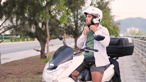 Helmet secured, the man prepares to start his moped engine. Video stock 312867786