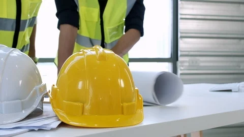 Helmets and papers on table with blur background architect talking with foreman. Stock Footage 126837415