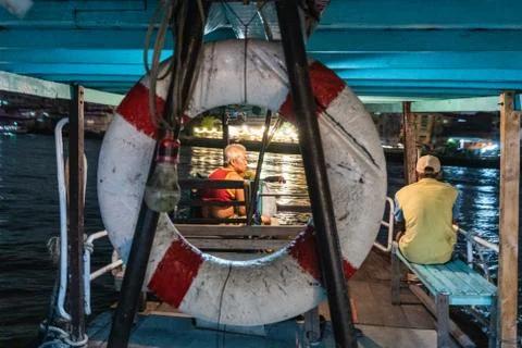Helmsman and his assistant on a small ferry in Bangkok Stock Photos