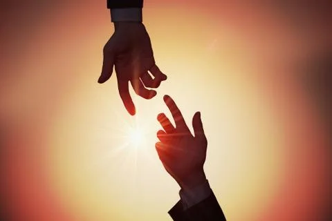 Help and assistance concept. Two hands are reaching each other at sunset. Foto stock
