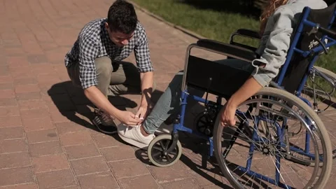 Help and support for disabled invalid people. Man tying her shoelaces disabled Stock Footage 154457030
