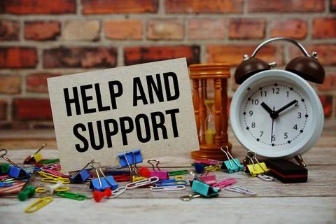 Help and Support text on paper card with alarm clock and stationary on wood.. 스톡 사진