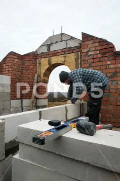 With the help of a glutinous solution, the worker builds a wall of gas blocks Stock Photos