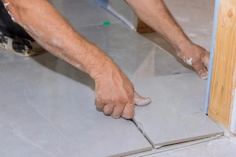 With the help of a home construction worker, placing ceramic tile on an adhesive Stock Photos