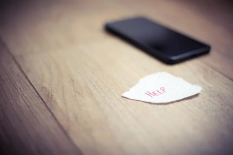 Help note on a wooden desk next to a cell phone Foto stock