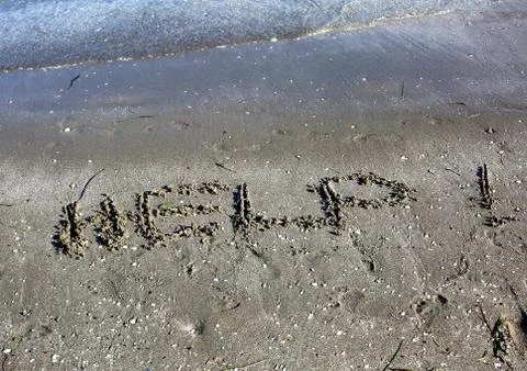 HELP text on sand by the sea Stockfoto's