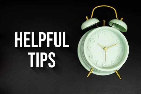 Helpful Tips text with alarm clock on black background Stock Photos