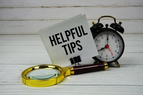 Helpful Tips text on paper card with alarm clock and magnifying glass on wo.. Stock Photos