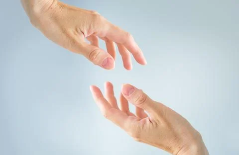 Helping concept hands reaching out to help each other isolated on light blu.. Stock Photos