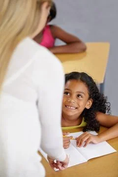 Helping her get to the answer. A teacher helping her student with her homework. Stock Photos