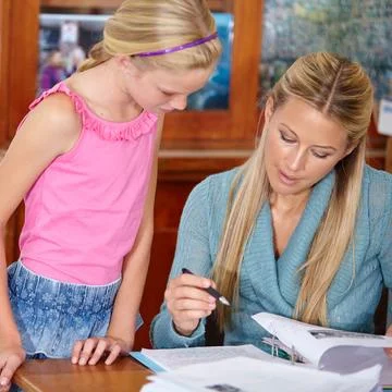 Helping her to get to the right answer. A young teacher explaining work to a Stock Photos