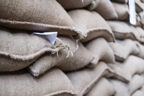 Hemp sacks containing coffee bean in warehouse. stacked sacks in storehouse. Stock Photos