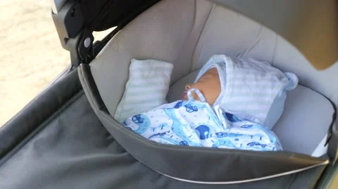 Hendheld shot of a gray pushchair with sleeping baby Stock Footage 67210579