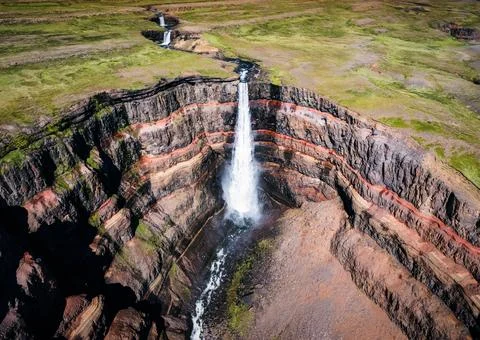 Hengifoss waterfall surrounded by layers of basaltic strata with water flow.. Stock Photos