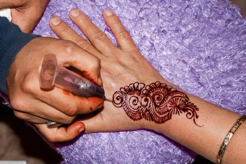 Henna artist applying henna on hand. Stock Photos