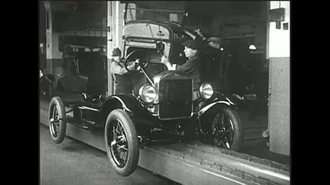 Henry Ford sits on the assembly line in the last Model T and Model T automobiles Stock Footage