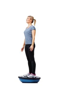 Her daily exercise routine. A beautiful young woman standing on a bosu-ball Foto stock