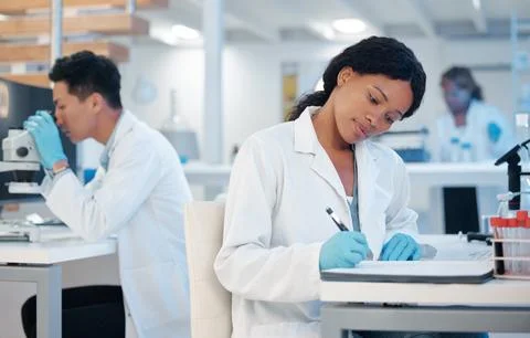 Her genius cannot be tamed. a young woman making notes while working in a lab. Foto stock