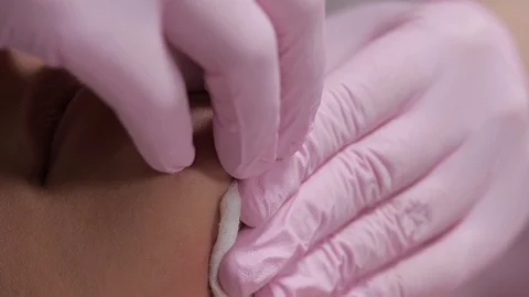 Her pink-gloved hands press the sterile bandage against her skin. Stock Footage 125799053