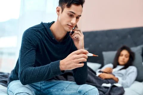 Her temperature seems stable at this time. a young man using a smartphone and Stock Photos