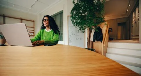 Her workday shows a work routine with phone and laptop at the office desk Stock Photos