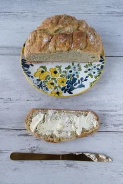 Herb bread on spring flower plate with buttered bread slice and knife top view Stock Photos