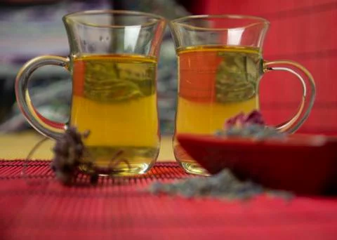 Herbal cold tea with lavender and oregano in glass cups on a yellow and red b Stock Photos
