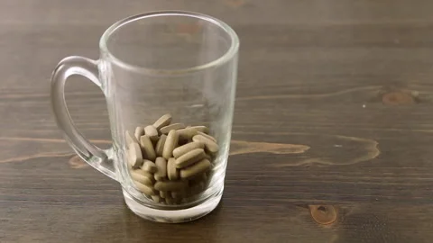 Herbal medicine tablets fall into a empty glass. Concept for self-medication Video stock 130399519