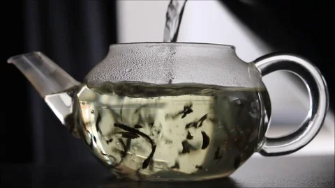 Herbal tea being poured into glass teapot Stock Footage