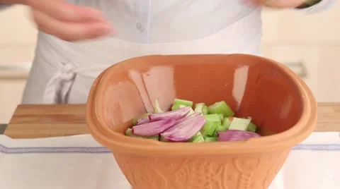 Herbs being added to vegetables in a terracotta baking dish 스톡 동영상 24657385