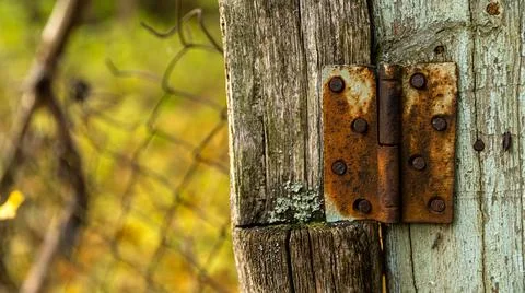 Here is a closeup image of a rusty door hinge attached to a wooden post Stock Photos